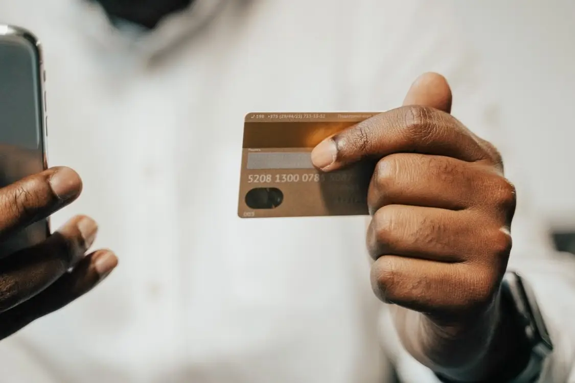 Hands holding a smartphone and a payment card.